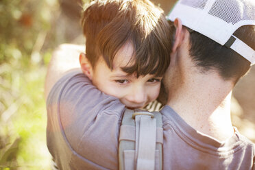Rückansicht eines Vaters, der seinen Sohn an einem sonnigen Tag umarmt - CAVF11107
