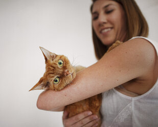 Side view of woman carrying cat at home - CAVF11118