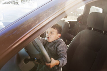 Junge tut so, als würde er fahren, während er im Auto sitzt - CAVF11146