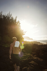 Rückansicht eines Mannes ohne Hemd, der an einem sonnigen Tag am Strand spazieren geht - CAVF11156