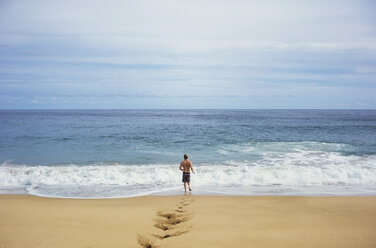 Rear view of man running on shore at beach against sky - CAVF11160