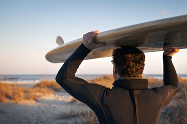 Nahaufnahme eines Surfers, der ein Surfbrett auf dem Kopf trägt, am Strand - CAVF11282