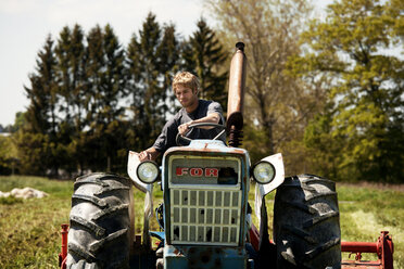 Landwirt zieht Egge mit Traktor auf einem Feld - CAVF11328