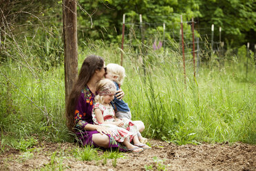 Children siting with mother on field - CAVF11422