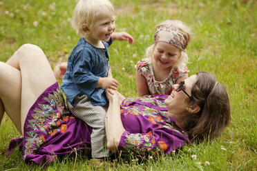 Mutter genießt mit Kindern auf einer Wiese - CAVF11428