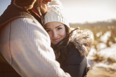 Nahaufnahme eines glücklichen Paares, das sich im Winter auf einem Feld umarmt - CAVF11450