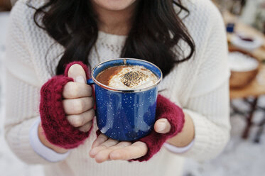 Close-up of woman holding coffee at backyard during winter - CAVF11454