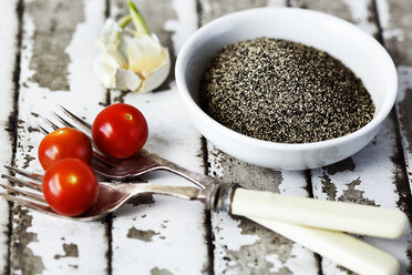 Schwarze Pfefferkörner und Kirschtomaten auf dem Tisch - CAVF11540