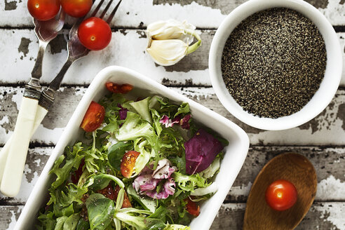 Salat mit schwarzen Pfefferkörnern und Kirschtomaten auf dem Tisch - CAVF11541