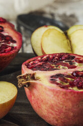 Close-up of apple and pomegranate on cutting board at table - CAVF11576