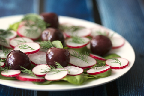 Nahaufnahme von Radieschen- und Kirschsalat mit Dillkräutern, serviert in einem Teller, lizenzfreies Stockfoto