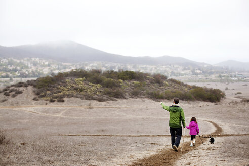 Rückansicht eines Vaters und eines Mädchens, die auf einem Feld gegen einen klaren Himmel laufen - CAVF11671