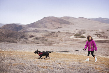 Girl with dog walking on field - CAVF11686