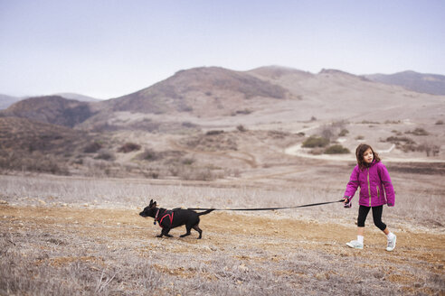 Mädchen mit Hund auf einem Feld spazierend - CAVF11686