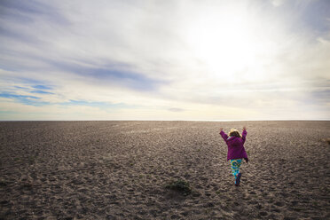Rückansicht eines Mädchens, das auf Sand gegen einen bewölkten Himmel läuft - CAVF11688