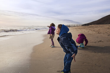 Sibling enjoying at beach against cloudy sky - CAVF11690