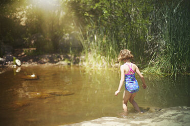 Rückansicht eines im Wasser gehenden Mädchens im Wald - CAVF11719