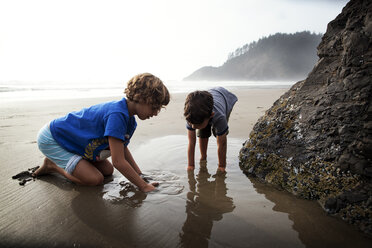 Children playing with wet sand on beach - CAVF11768