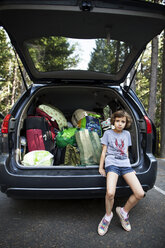 Porträt eines Mädchens auf dem Kofferraum eines Autos sitzend auf der Straße - CAVF11795