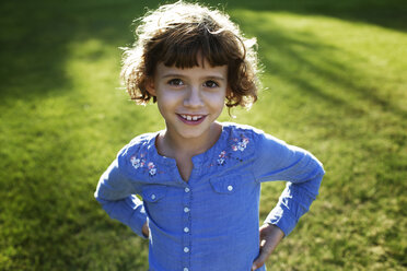 Porträt eines Mädchens, das im Park steht und die Hände in die Hüften stemmt - CAVF11800