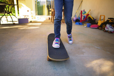 Niedriger Ausschnitt eines Mädchens, das im Hinterhof Skateboard fahren lernt - CAVF11808