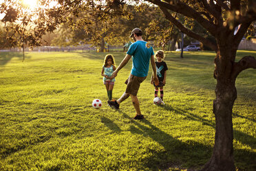 Vater spielt Fußball mit Töchtern im Park - CAVF11811