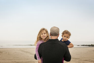Vater trägt Töchter am Strand gegen den klaren Himmel - CAVF11819