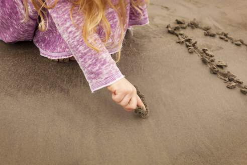 Ausgeschnittenes Bild eines Mädchens, das am Strand auf Sand schreibt - CAVF11821