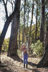 Mädchen hält Stock, während sie im Wald steht - CAVF11826