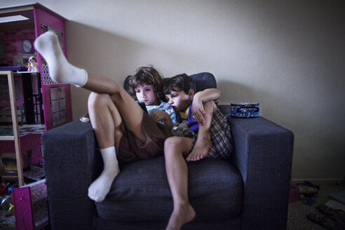Geschwisterkind benutzt ein Handheld-Videospiel, während es zu Hause auf dem Sofa sitzt - CAVF11847