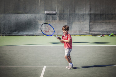 Junge hält Tennisschläger, während er auf dem Platz steht - CAVF11860