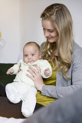 Smiling mother with her baby boy sitting on couch - BMOF00041