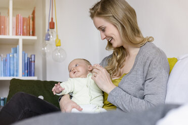 Smiling mother with her baby boy sitting on couch - BMOF00042