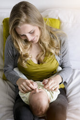 Smiling mother with her baby boy, lying on lap - BMOF00047