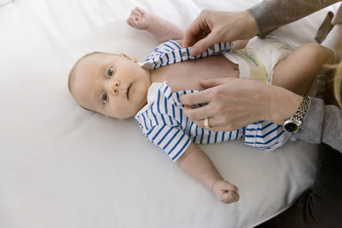 Mutter, die einen kleinen Jungen auf der Couch anzieht, lizenzfreies Stockfoto