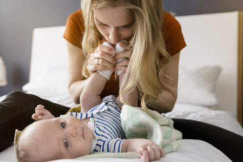Mother kissing baby boy's feet stock photo