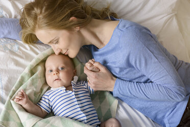 Mutter mit ihrem kleinen Jungen, der sich auf dem Bett an den Händen hält - BMOF00064