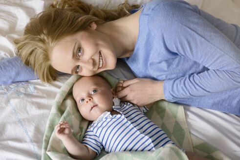 Porträt einer lächelnden Mutter mit ihrem kleinen Jungen auf dem Bett liegend - BMOF00065