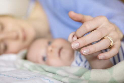 Mutter hält die Hände des kleinen Jungen auf dem Bett, Nahaufnahme - BMOF00066