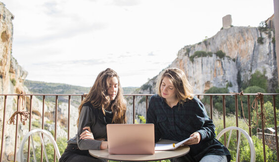 Spain, Alquezar, two women working together with laptop on terrace - AFVF00340