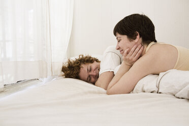 Lächelndes Paar entspannt sich auf dem Bett zu Hause - CAVF11977