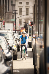 Man cycling in city on sunny day - CAVF11988