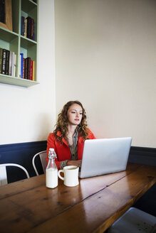 Frau, die einen Laptop benutzt, während sie in einem Café sitzt - CAVF12001