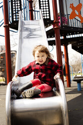 Portrait of cute girl sitting on slide at playground - CAVF12045
