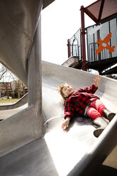 Girl lying on slide at playground - CAVF12046
