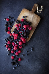 High angle view of berry fruits and cutting board on slate - CAVF12102