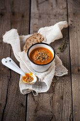 Overhead view of carrot soup in bowls with bread and rosemary on wooden table - CAVF12133