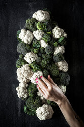 Cropped hand of woman touching broccoli and cauliflower on table - CAVF12157