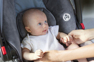 Ausgeschnittenes Bild von Händen, die ein Baby im Autositz halten - CAVF12284