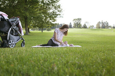 Mutter spielt mit Baby und ruht sich auf einer Wiese im Park aus - CAVF12286